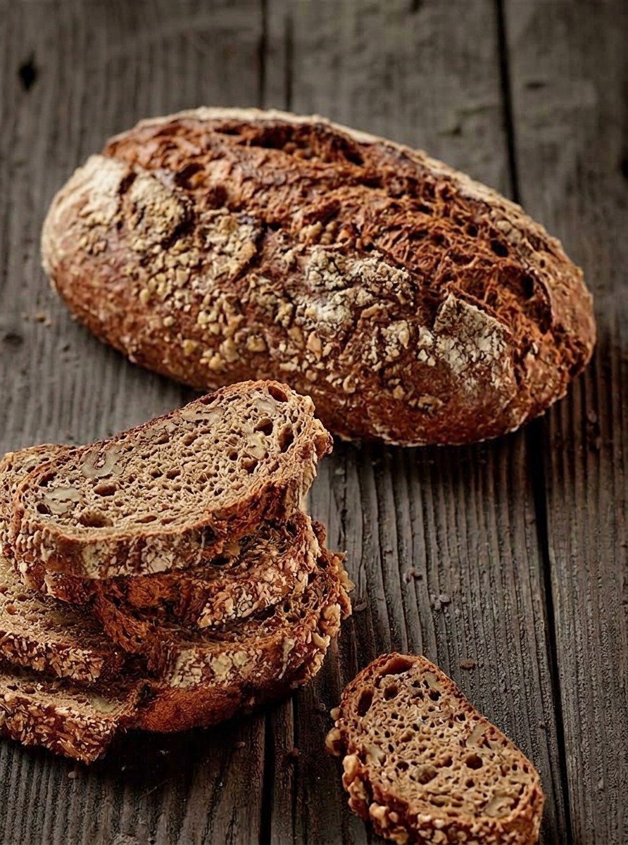 Dinkel-Walnuss-Brot, ganz und in Scheiben, auf einem Holztisch